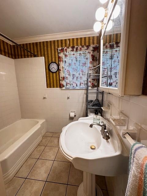 bathroom with tile patterned floors, wallpapered walls, ornamental molding, and tile walls