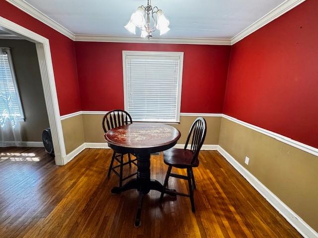 dining area featuring ornamental molding, baseboards, a chandelier, and wood finished floors