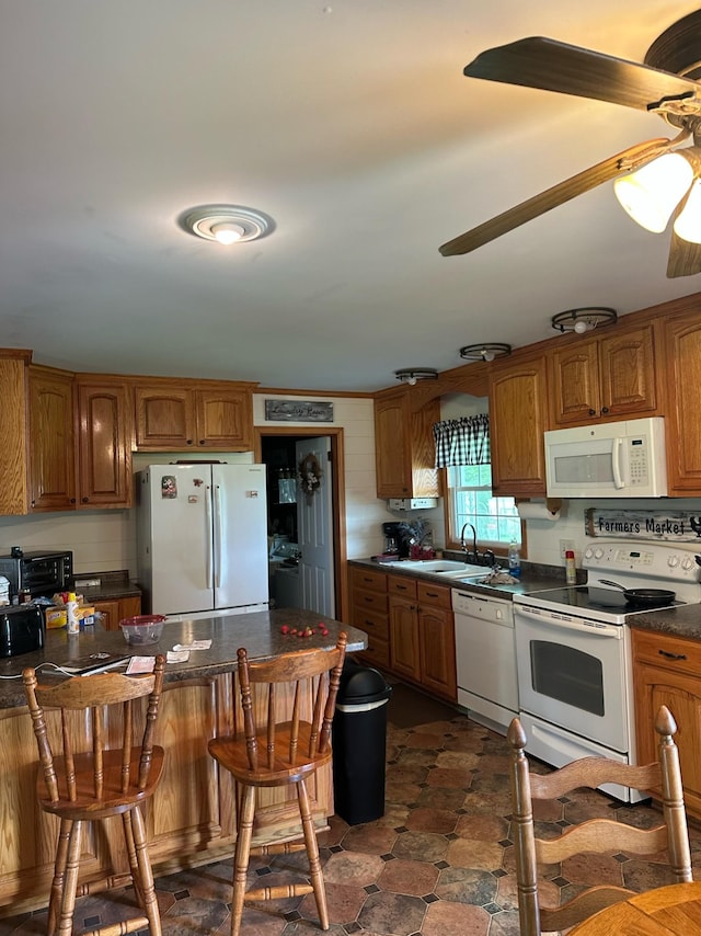 2901 Hurricane Creek Rd, Lawrenceburg, TN 38464 - kitchen with a ceiling fan, dark countertops, a kitchen breakfast bar, a sink, and white appliances