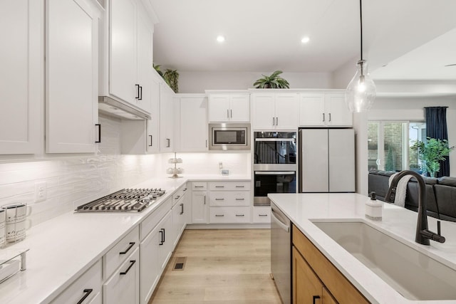 kitchen featuring a sink, white cabinetry, backsplash, and stainless steel appliances