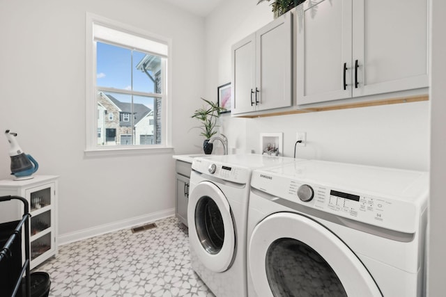 laundry room featuring visible vents, washing machine and dryer, cabinet space, baseboards, and light floors