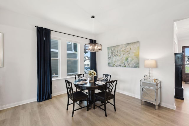 dining room featuring baseboards, light wood-style flooring, and a chandelier