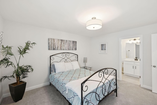bedroom featuring light colored carpet, a sink, baseboards, and ensuite bath