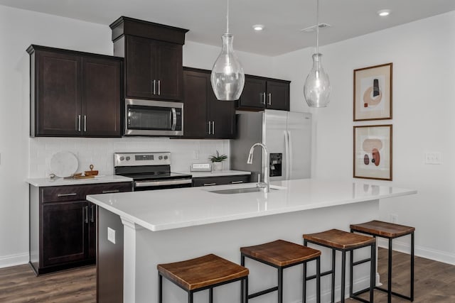 kitchen with a sink, tasteful backsplash, appliances with stainless steel finishes, and dark wood finished floors
