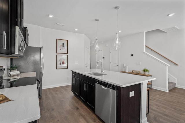 kitchen featuring dark wood-type flooring, a kitchen island with sink, visible vents, stainless steel appliances, and a sink
