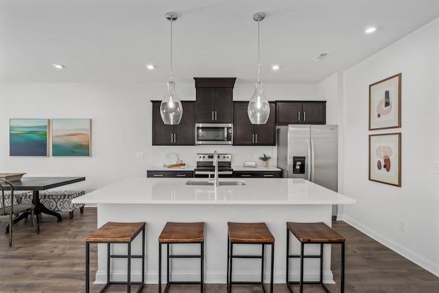 kitchen with dark wood-style floors, a breakfast bar area, and stainless steel appliances