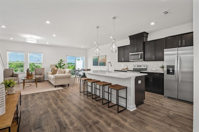 kitchen featuring a breakfast bar, open floor plan, visible vents, stainless steel appliances, and a sink