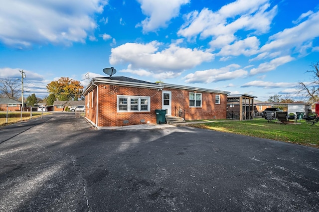 view of front of house with brick siding, a front lawn, crawl space, and aphalt driveway