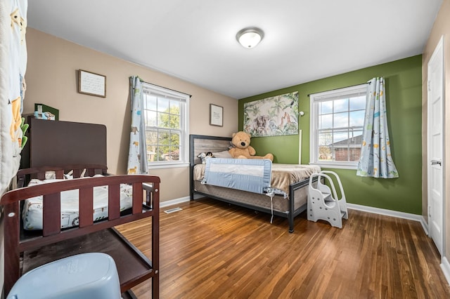 bedroom with wood finished floors, baseboards, and visible vents