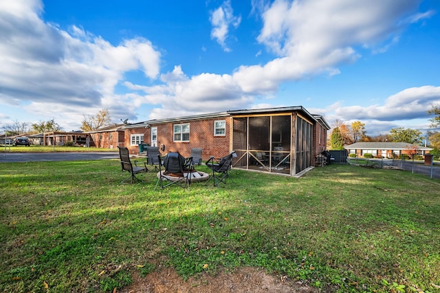 back of house with a sunroom, a yard, fence, and brick siding