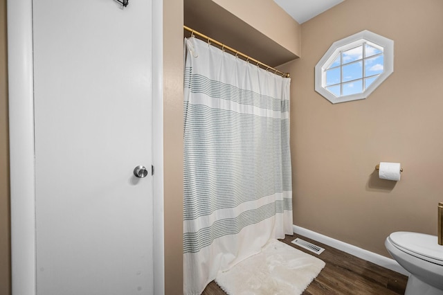 bathroom featuring a shower with shower curtain, baseboards, toilet, visible vents, and wood finished floors