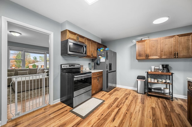 kitchen with light wood finished floors, baseboards, and stainless steel appliances