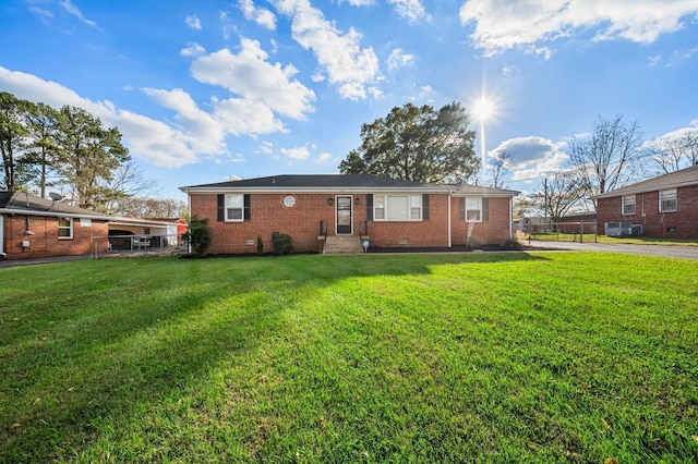 rear view of house with brick siding, crawl space, fence, and a lawn