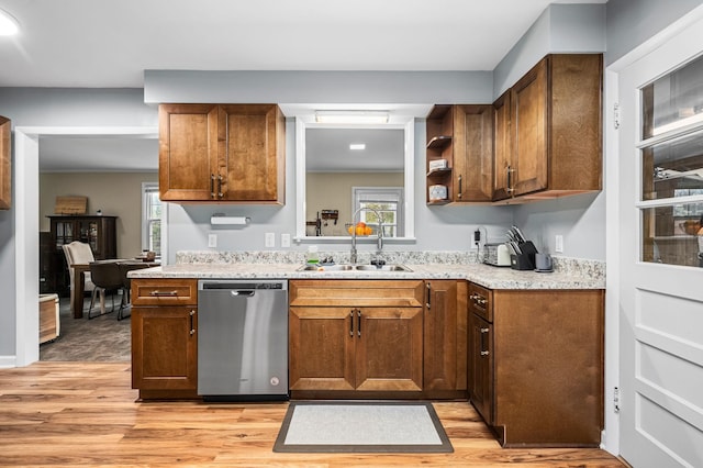 kitchen with light wood finished floors, stainless steel dishwasher, a sink, and a wealth of natural light