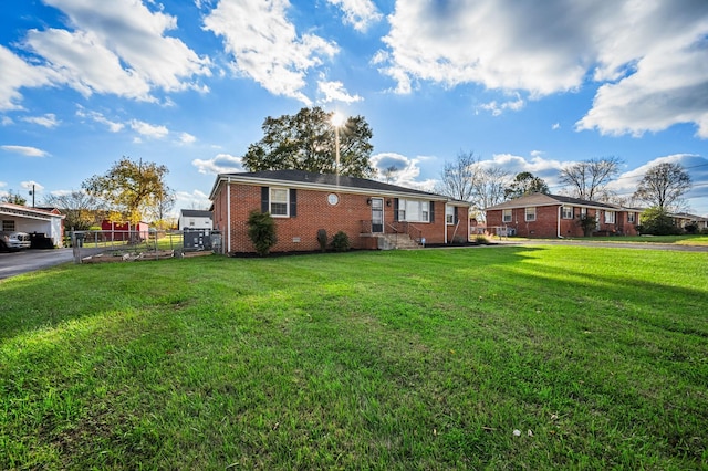 rear view of property featuring brick siding, fence, and a lawn