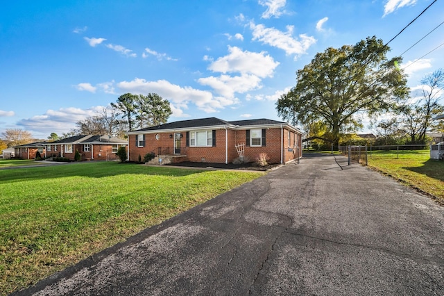 view of front of property featuring driveway, a front yard, fence, and brick siding