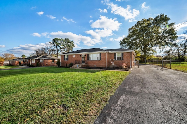 ranch-style home with brick siding, a front lawn, fence, and driveway