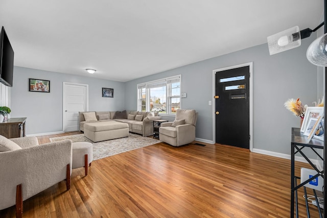 living room with wood finished floors, baseboards, and visible vents