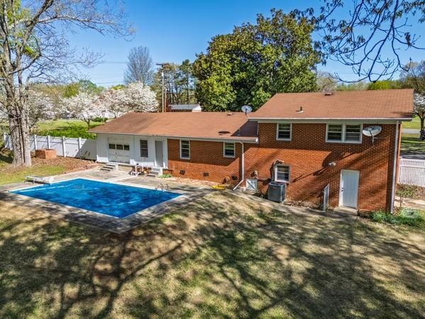 rear view of house with entry steps, fence, a patio, brick siding, and a fenced in pool