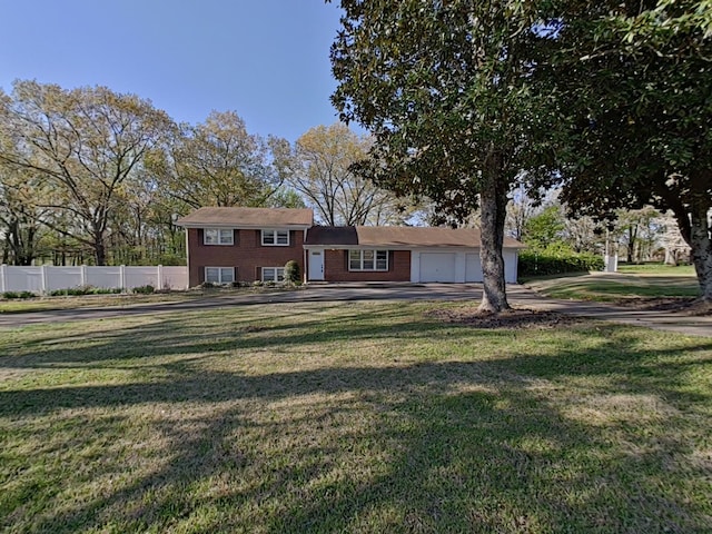 split level home featuring brick siding, a front lawn, fence, and an attached garage