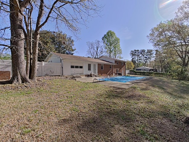 rear view of property featuring a lawn, a garage, a fenced backyard, a patio, and a fenced in pool