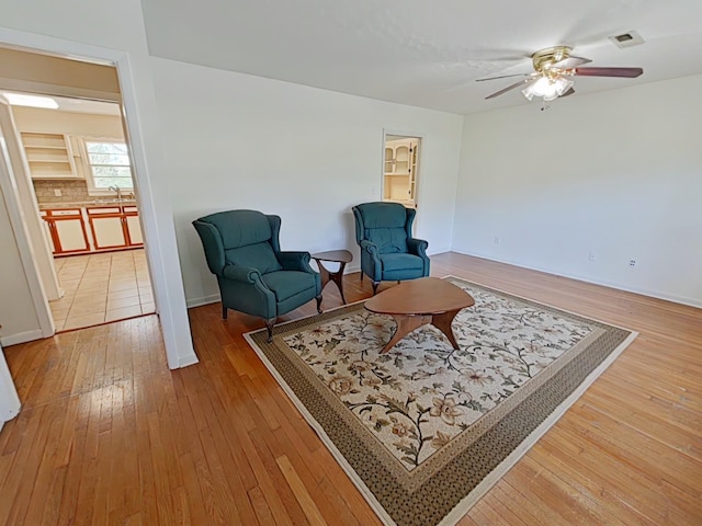 living area featuring light wood-style flooring, a ceiling fan, and visible vents