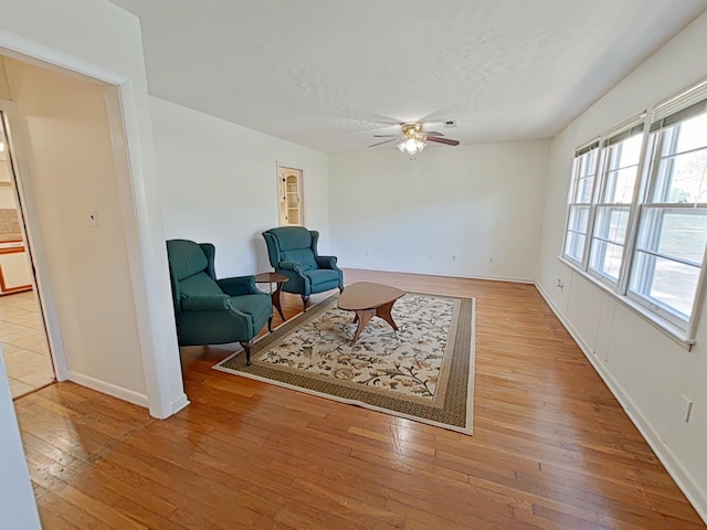 sitting room featuring light wood-style flooring, ceiling fan, baseboards, and a textured ceiling