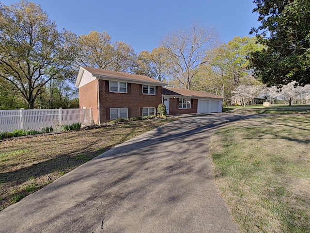 view of front of property with an attached garage, aphalt driveway, fence, brick siding, and a front lawn