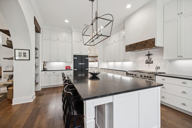 kitchen featuring custom range hood, dark wood-style flooring, a chandelier, dark countertops, and high end stove