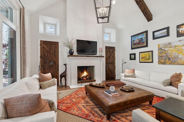 living room featuring a fireplace with flush hearth, a chandelier, high vaulted ceiling, and a wealth of natural light
