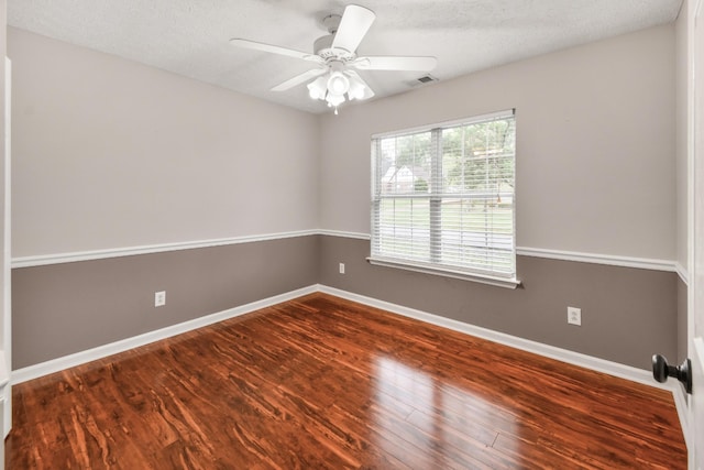 spare room with wood finished floors, ceiling fan, baseboards, and visible vents