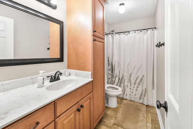 bathroom with toilet, a textured ceiling, stone finish floor, and vanity