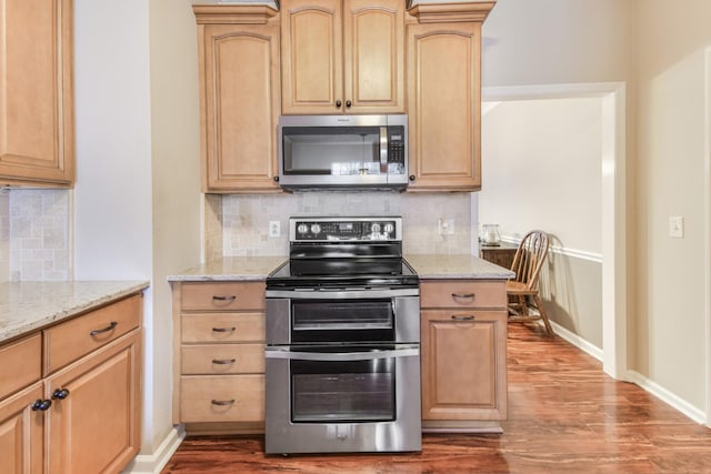 kitchen featuring stainless steel appliances, light brown cabinetry, and wood finished floors