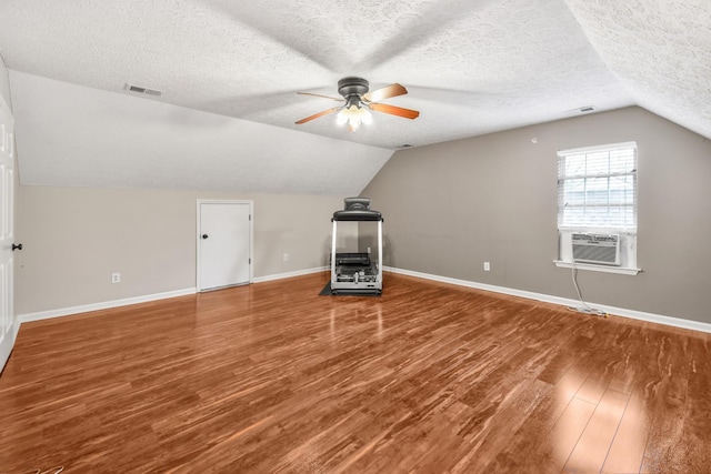 additional living space featuring baseboards, vaulted ceiling, visible vents, ceiling fan, and wood finished floors
