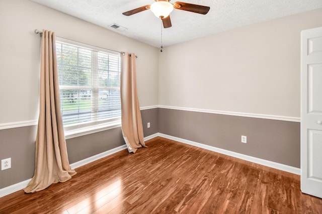 unfurnished room with baseboards, a ceiling fan, wood finished floors, and a textured ceiling