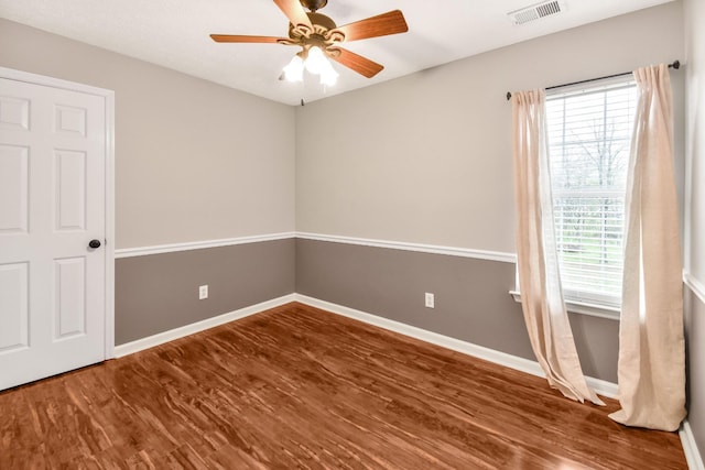 spare room featuring wood finished floors, baseboards, a ceiling fan, and visible vents