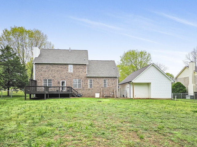 back of house with a chimney, a yard, a deck, and brick siding