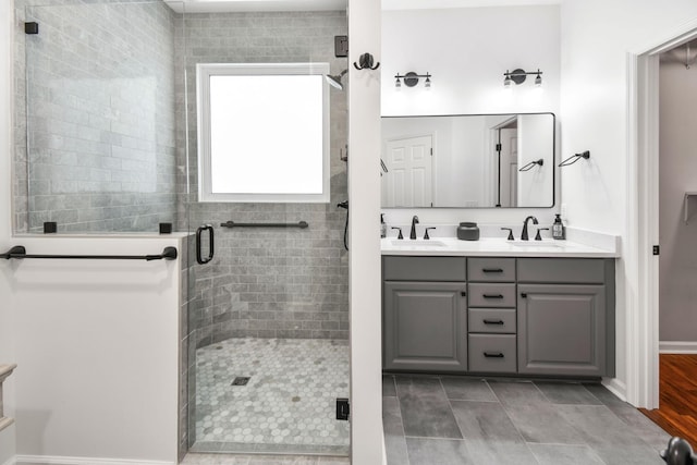 bathroom with a sink, a shower stall, and double vanity