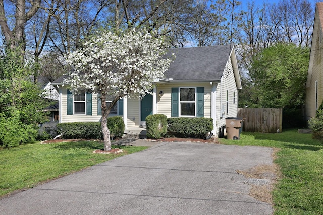 view of front facade with a front lawn, fence, and roof with shingles