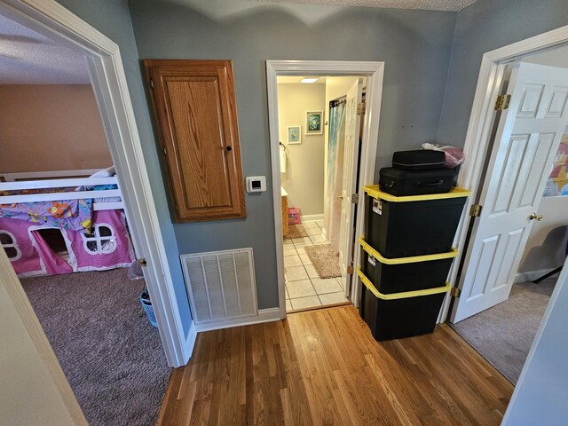 hall featuring wood finished floors, visible vents, and baseboards
