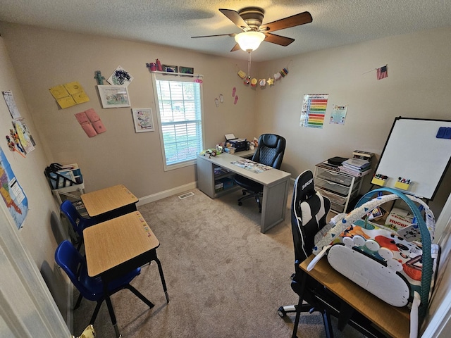carpeted office with baseboards, visible vents, a ceiling fan, and a textured ceiling