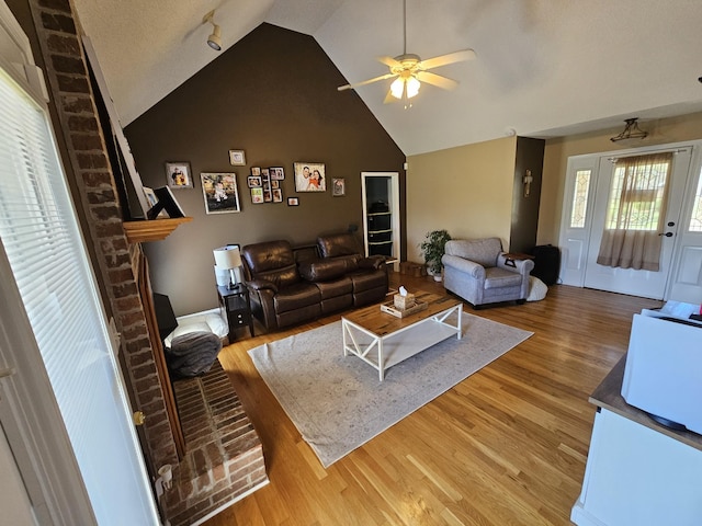 living area with light wood finished floors, a ceiling fan, and high vaulted ceiling