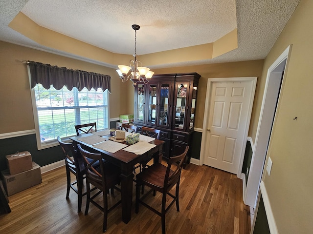 dining room featuring an inviting chandelier, a tray ceiling, dark wood-type flooring, baseboards, and a textured ceiling