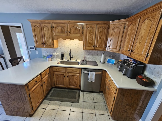 kitchen featuring stainless steel dishwasher, a sink, light countertops, a peninsula, and brown cabinetry