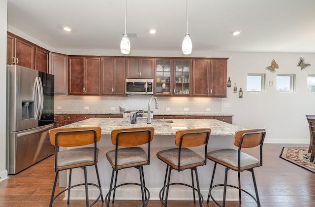 359 Mattieton Ln, Gallatin, TN 37066 - kitchen with a kitchen bar, appliances with stainless steel finishes, light stone counters, wood finished floors, and decorative backsplash