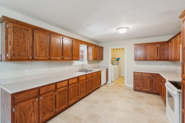 kitchen featuring light countertops, white appliances, washing machine and clothes dryer, and a sink