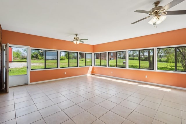 unfurnished sunroom featuring baseboards, tile patterned flooring, and a wealth of natural light