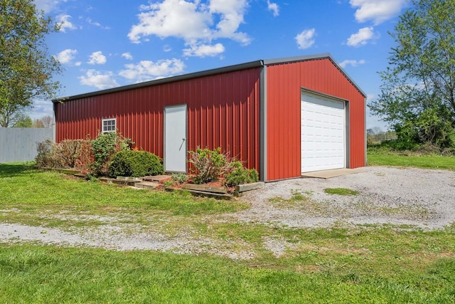 detached garage featuring fence and gravel driveway