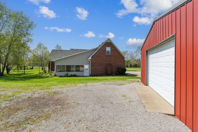view of property exterior featuring brick siding, a garage, a lawn, and gravel driveway
