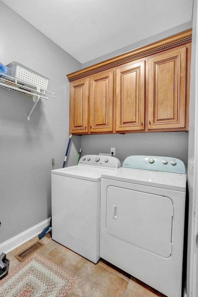 clothes washing area featuring visible vents, washer and clothes dryer, baseboards, and cabinet space